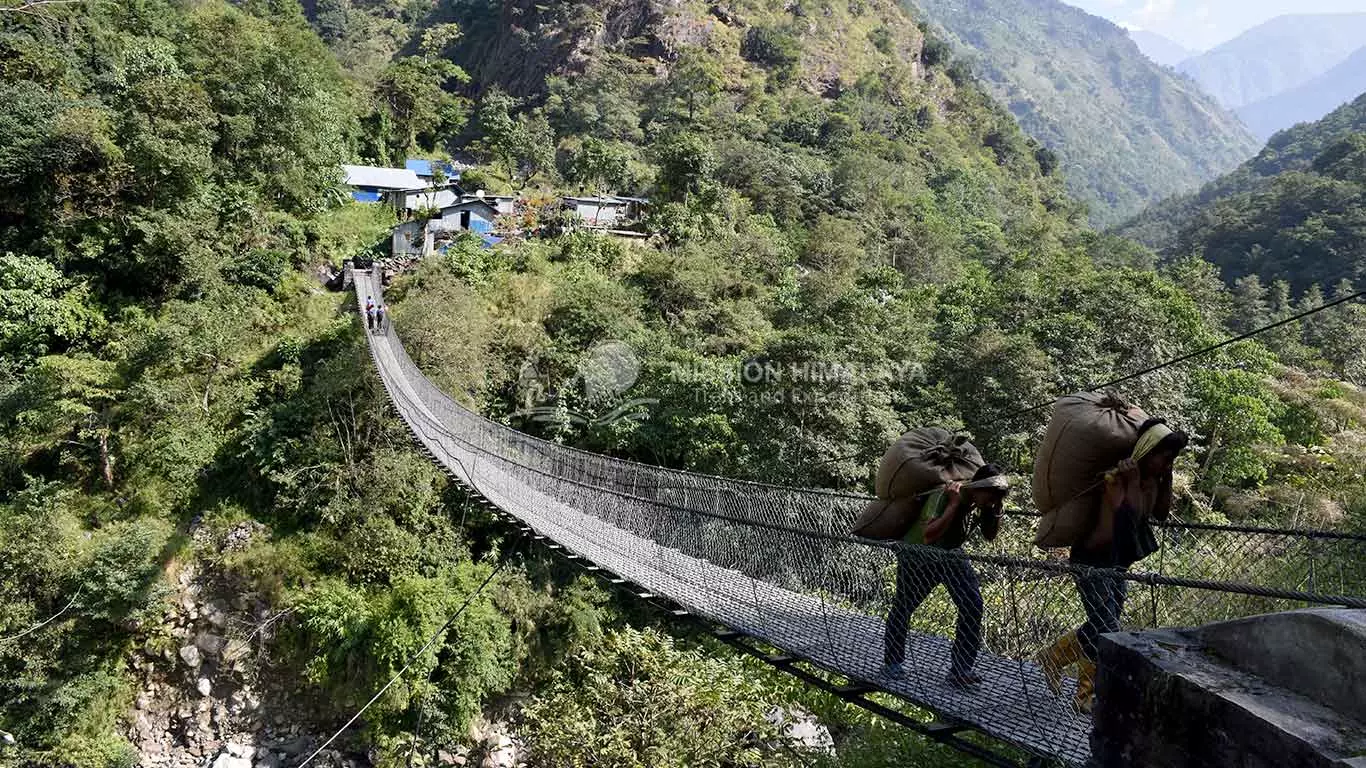 porters crossing suspension bridge with sack of rice